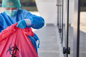 trauma scene & biohazard cleanup technician safely handling red biohazard waste bag