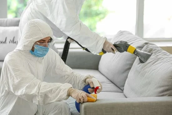 Trauma scene & biohazard cleanup service technicians cleaning contaminated furniture in full PPE.